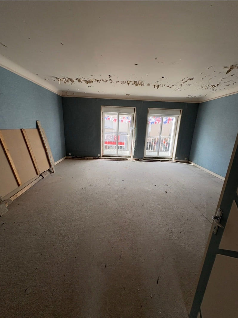 Séjour avant les travaux de peinture, murs bleus et plafond abîmé