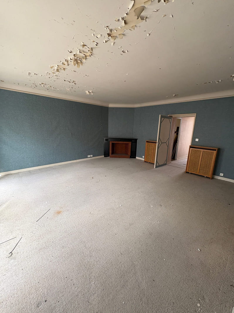 Pièce de vie avant travaux, papier peint bleu et peinture de plafond écaillée